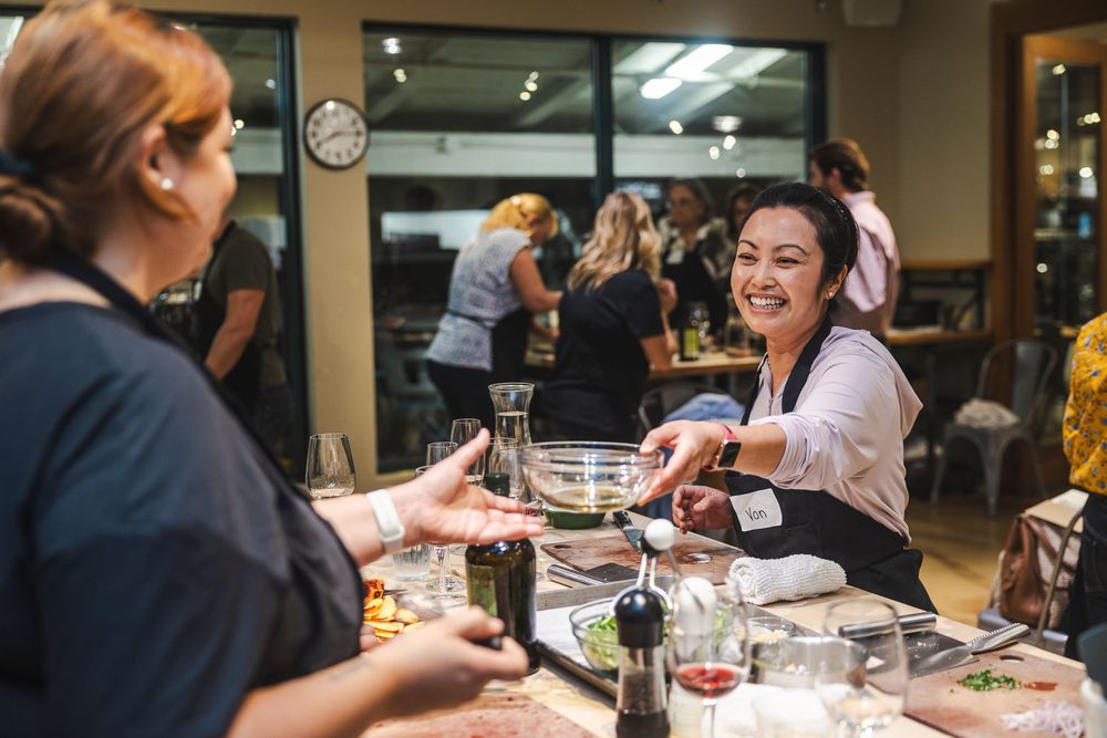A group of people enjoying wine and conversation at a restaurant table during a social gathering.