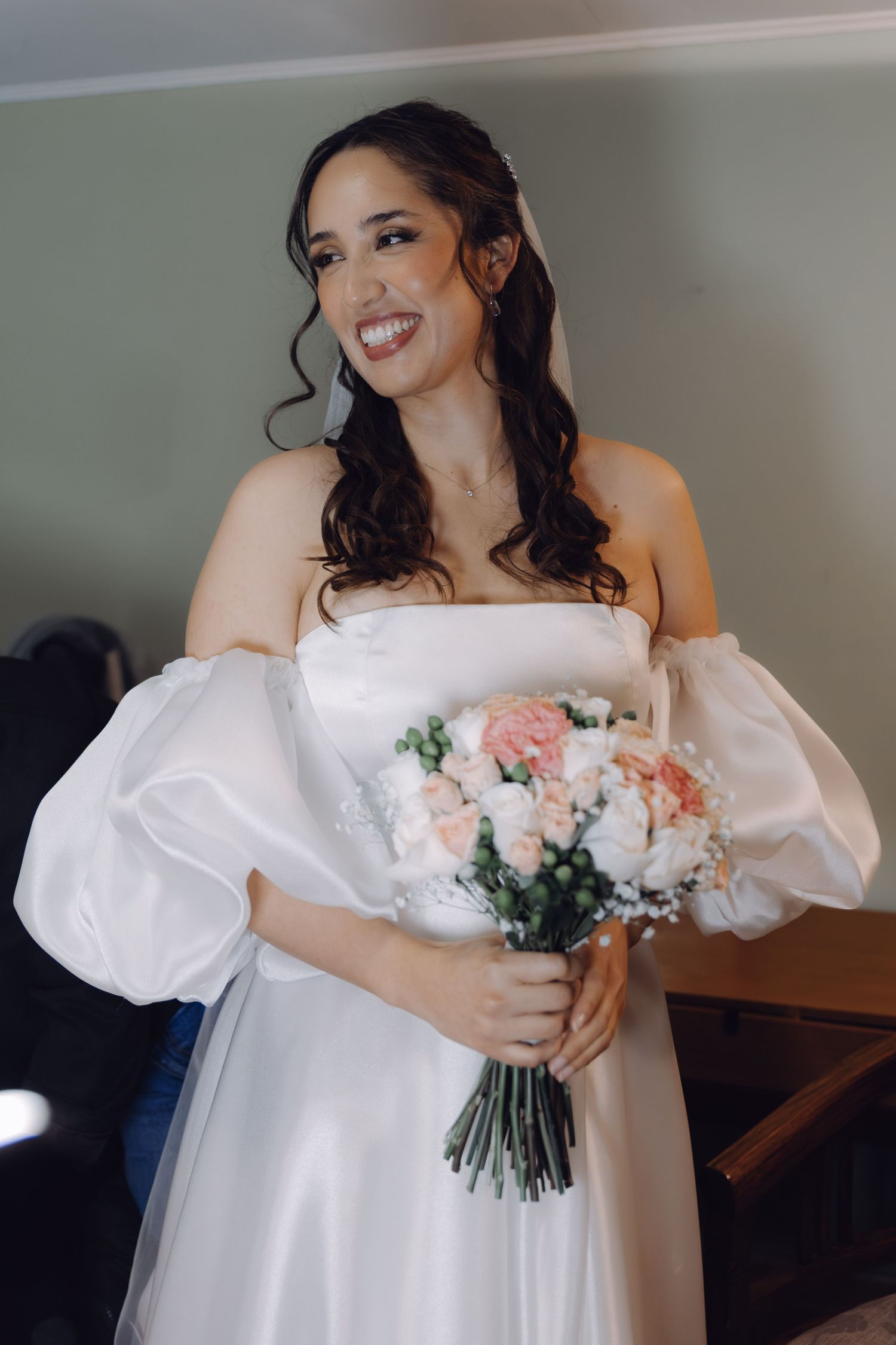 Radiant bride in white off-shoulder gown holding pink and white bridal bouquet.