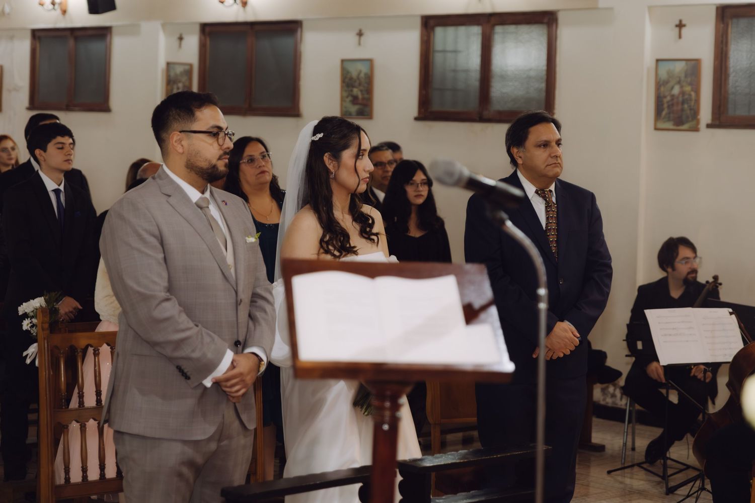 Bride and groom standing at church altar with officiant during wedding ceremony.