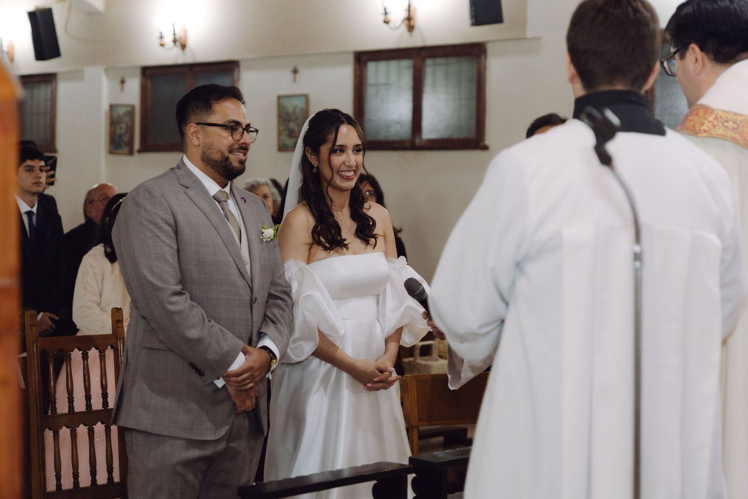 Bride and groom exchanging vows before priest at Catholic church wedding ceremony.