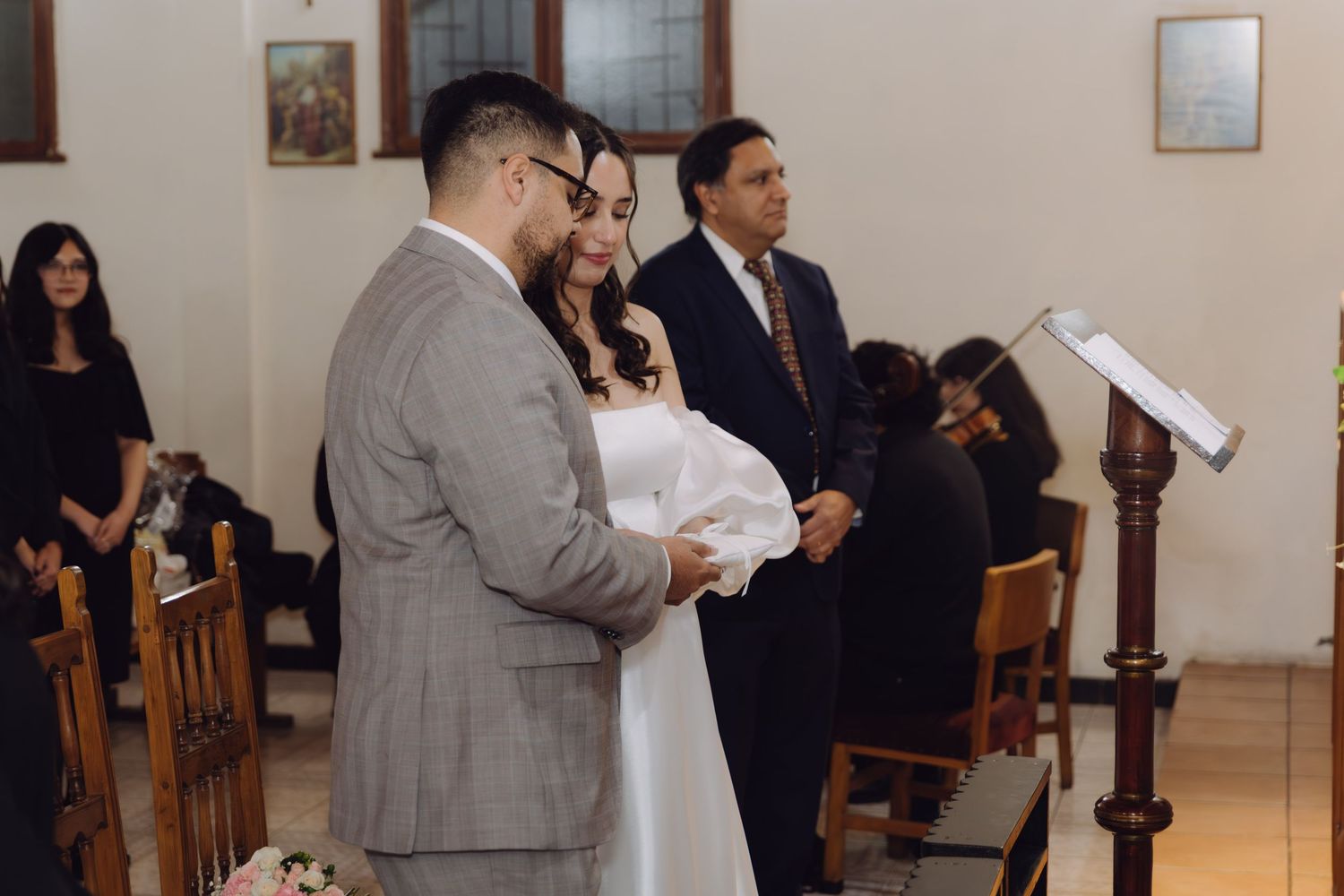 Bride and groom stand together at the altar during a church wedding ceremony with guests seated in pews.