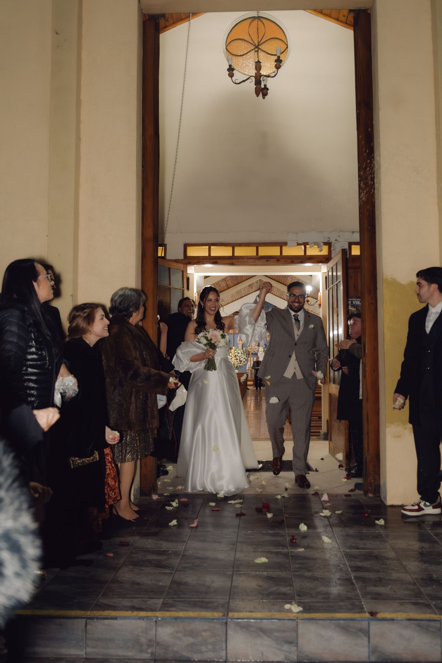 Bride and groom walk down the aisle as wedding guests line up to celebrate their ceremony exit.