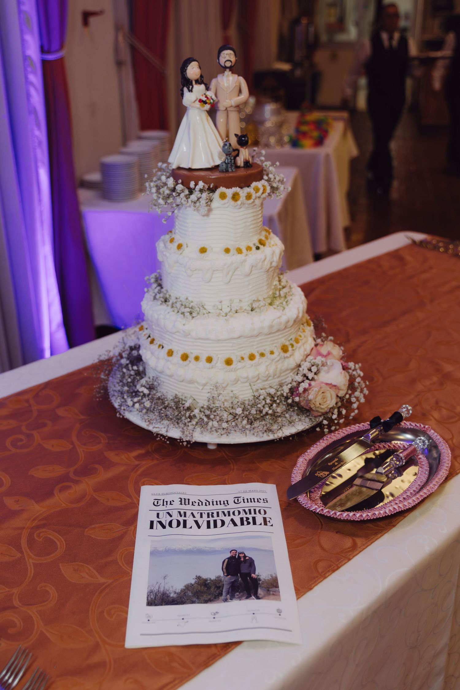 Elegant four-tier white wedding cake with floral decor and bride and groom cake topper.