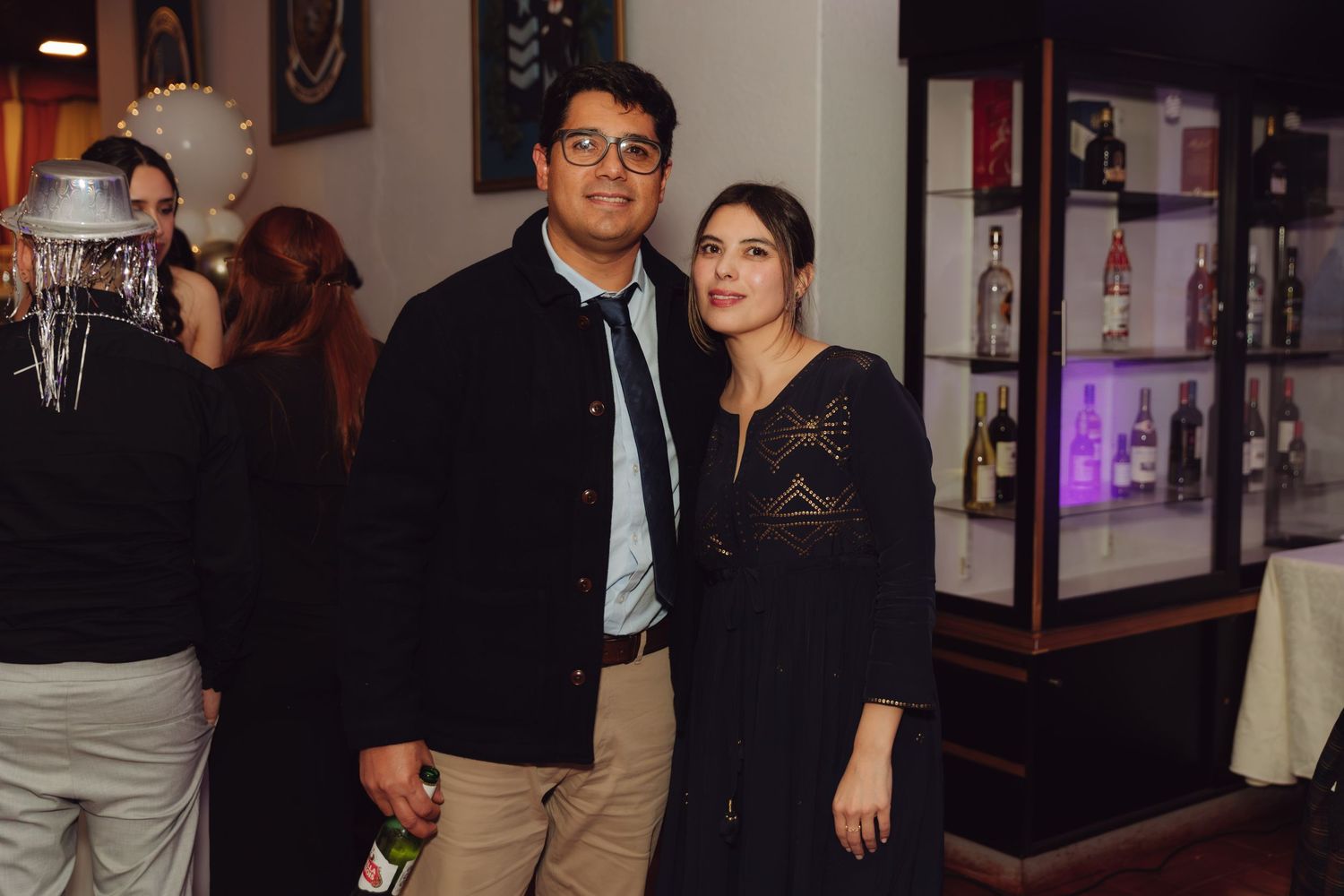 Elegant couple posing together at wedding reception venue with decorative display cases in background.