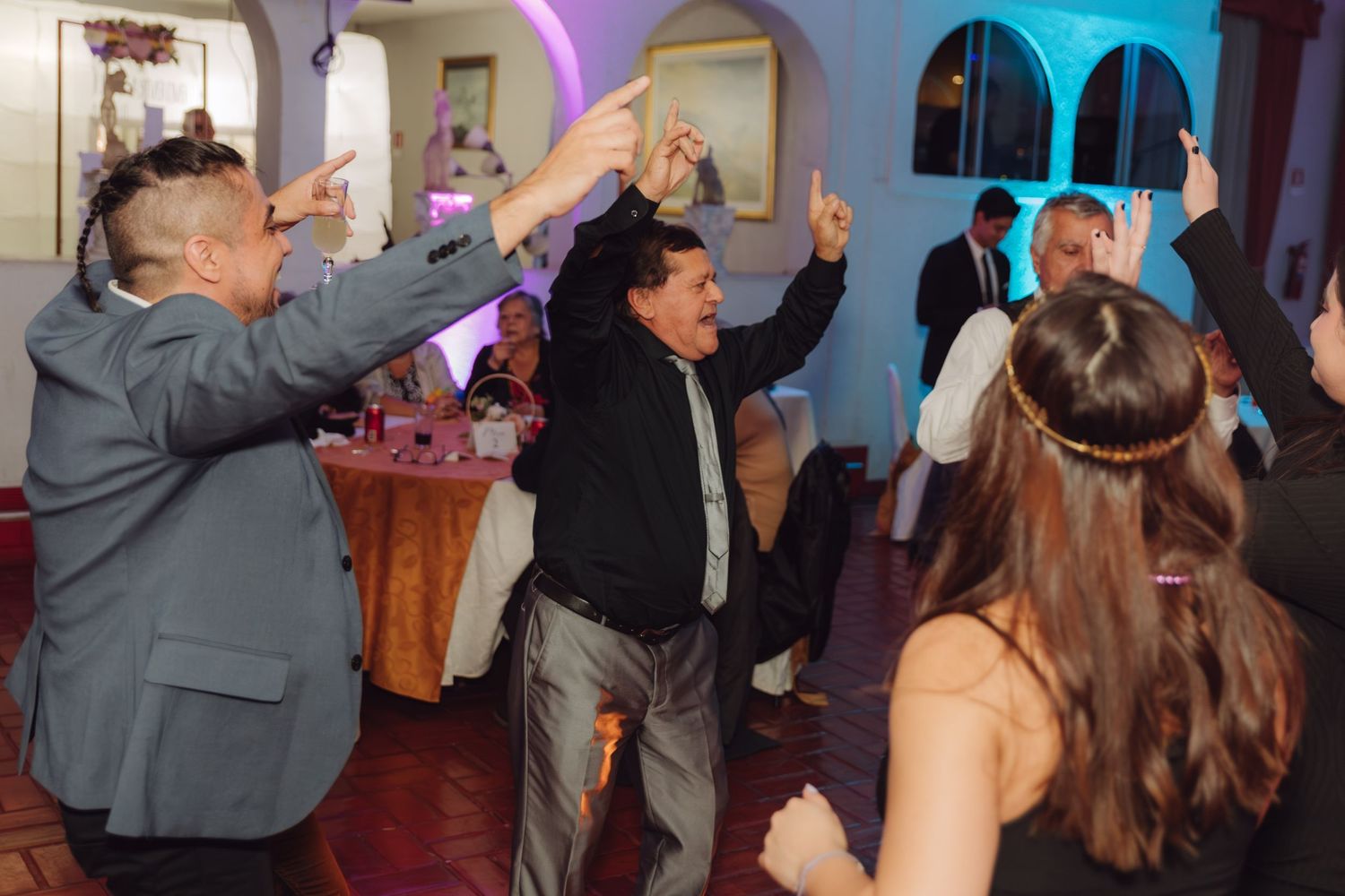 Guests dancing energetically with hands raised at a lively wedding reception party.