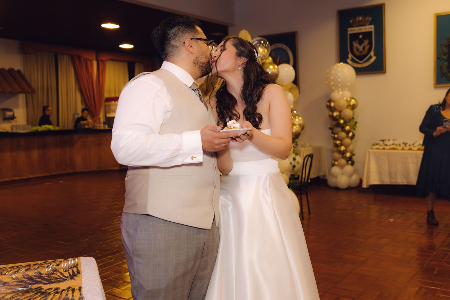 Newlyweds sharing a romantic kiss after cutting the wedding cake at their reception.