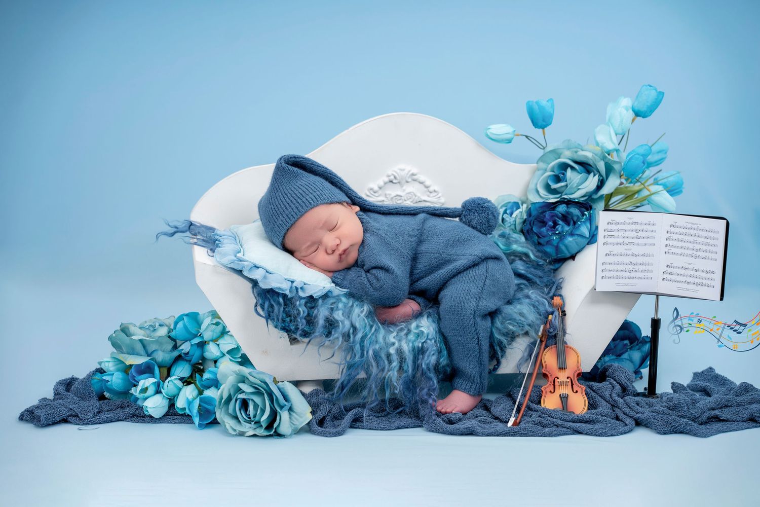 Newborn baby sleeping peacefully in blue tones with floral decorations and books in a creative photo collage.