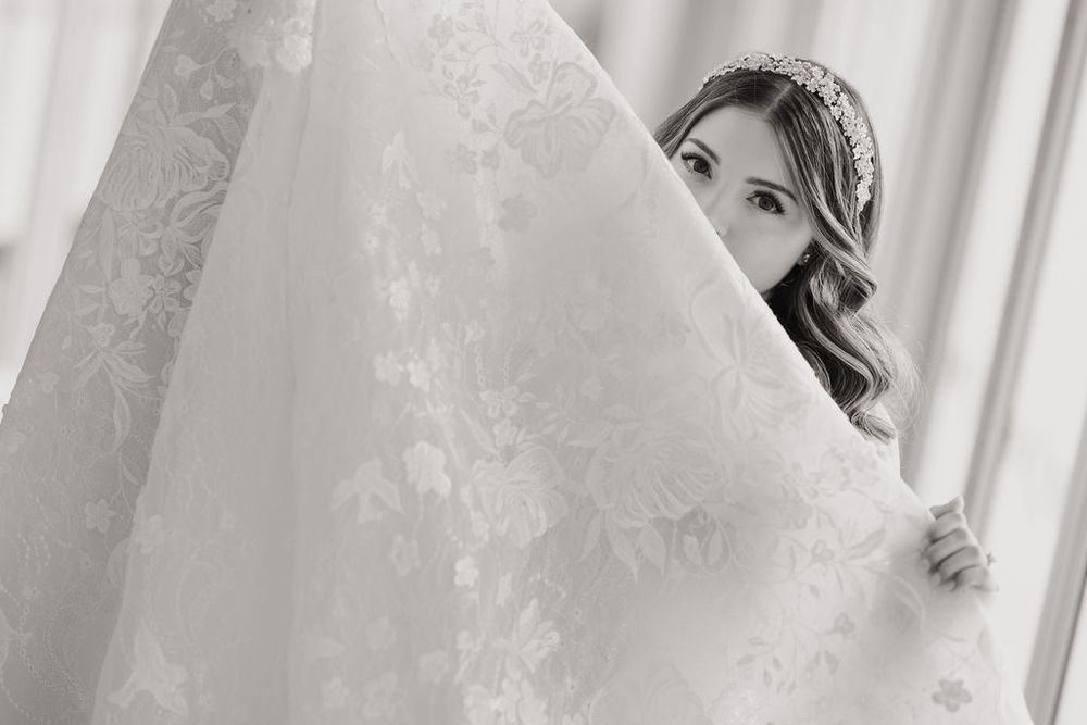 A couple shares a romantic kiss while standing in front of white curtains in a bright, airy setting.