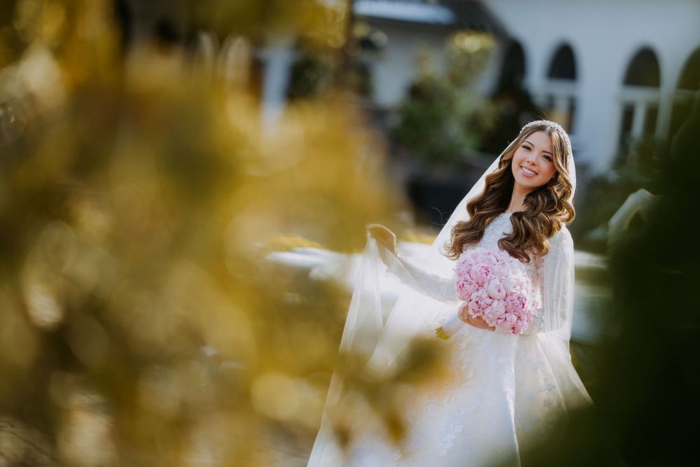 Romantic outdoor wedding photo shoot with couple in formal attire surrounded by autumn foliage.