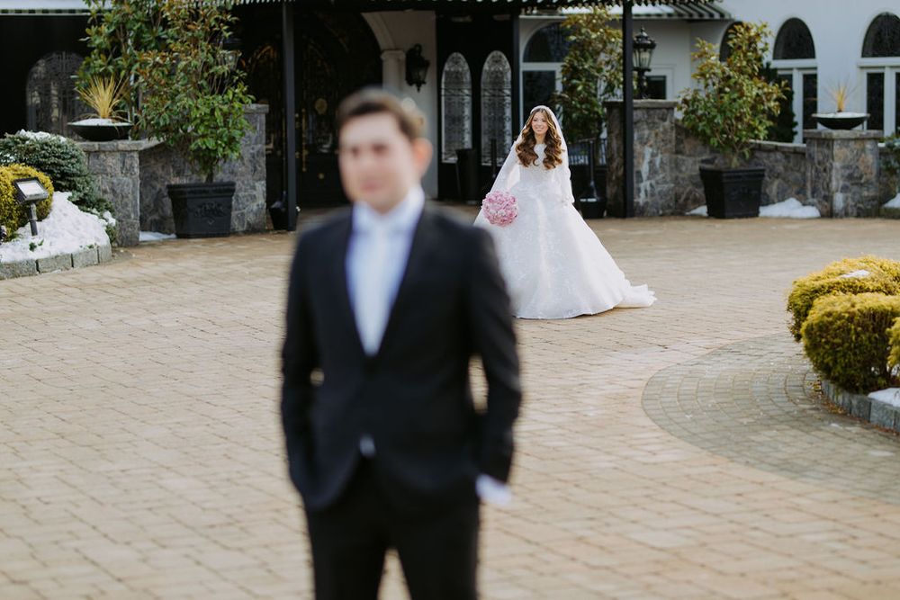 A wedding couple doing a first look moment in a courtyard with stone architecture and landscaping.