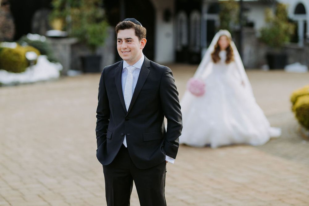 Wedding photoshoot outdoors with couple in formal attire near stone building.