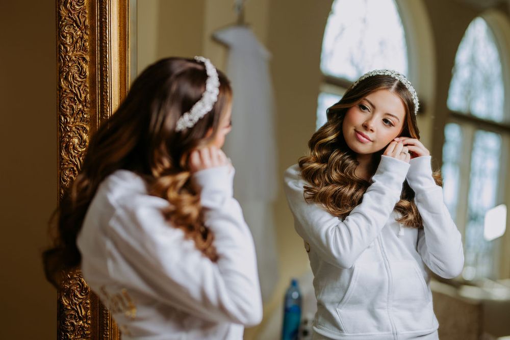 A person in a white sweater stands near a window with natural light streaming in, creating a soft, dreamy atmosphere.