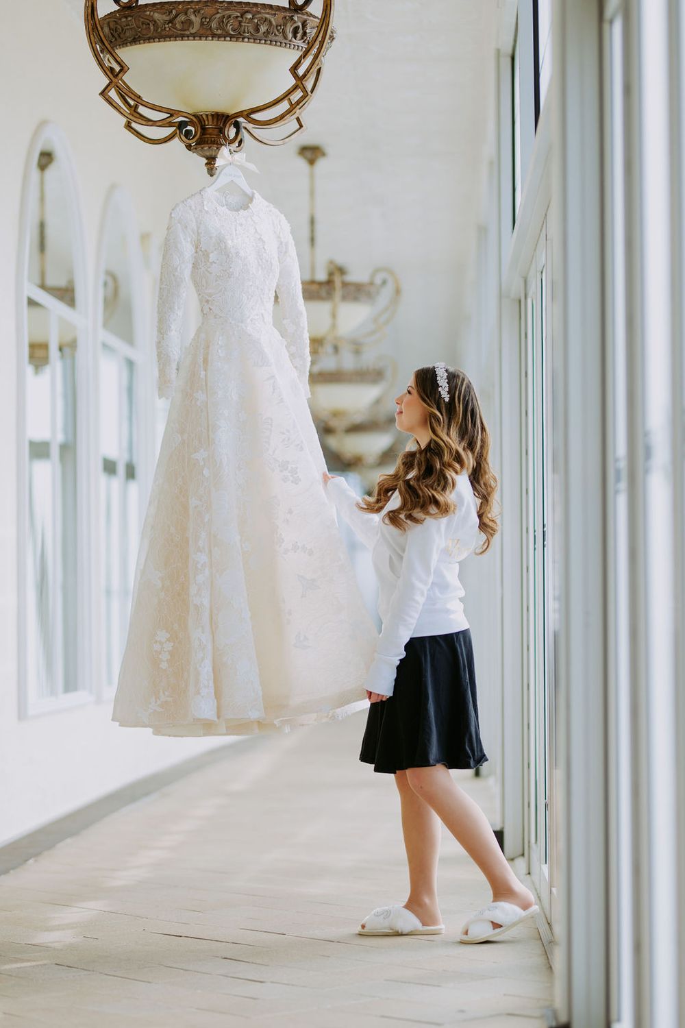 An elegant hallway displays wedding dresses while a person in casual attire walks through.