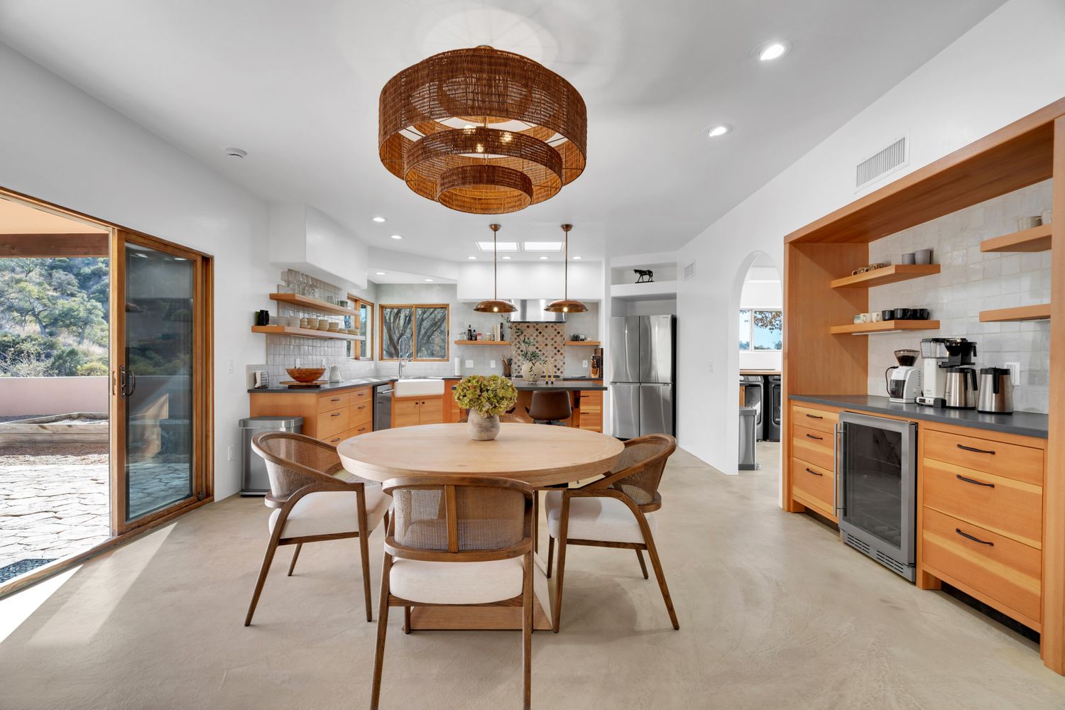 Modern kitchen and dining area with wooden cabinetry and sleek white walls showcasing open concept design.