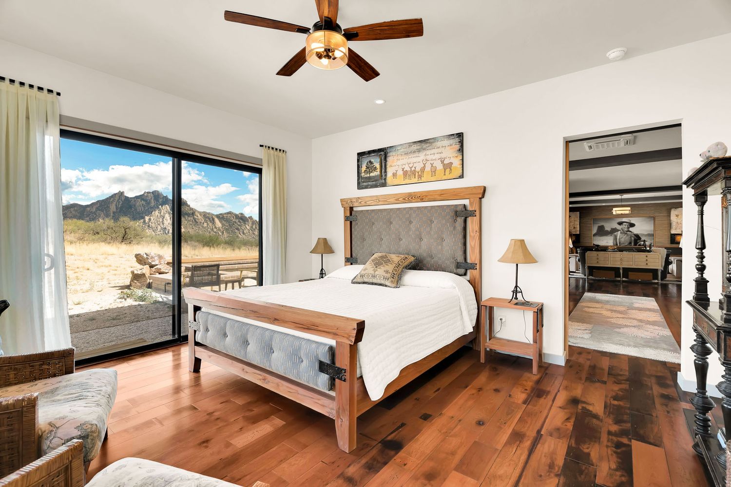 Modern rustic bedroom with wooden floors, mountain views through large windows, and four-poster bed.