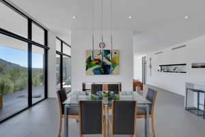 Modern minimalist living room and dining area with floor-to-ceiling windows offering mountain views.