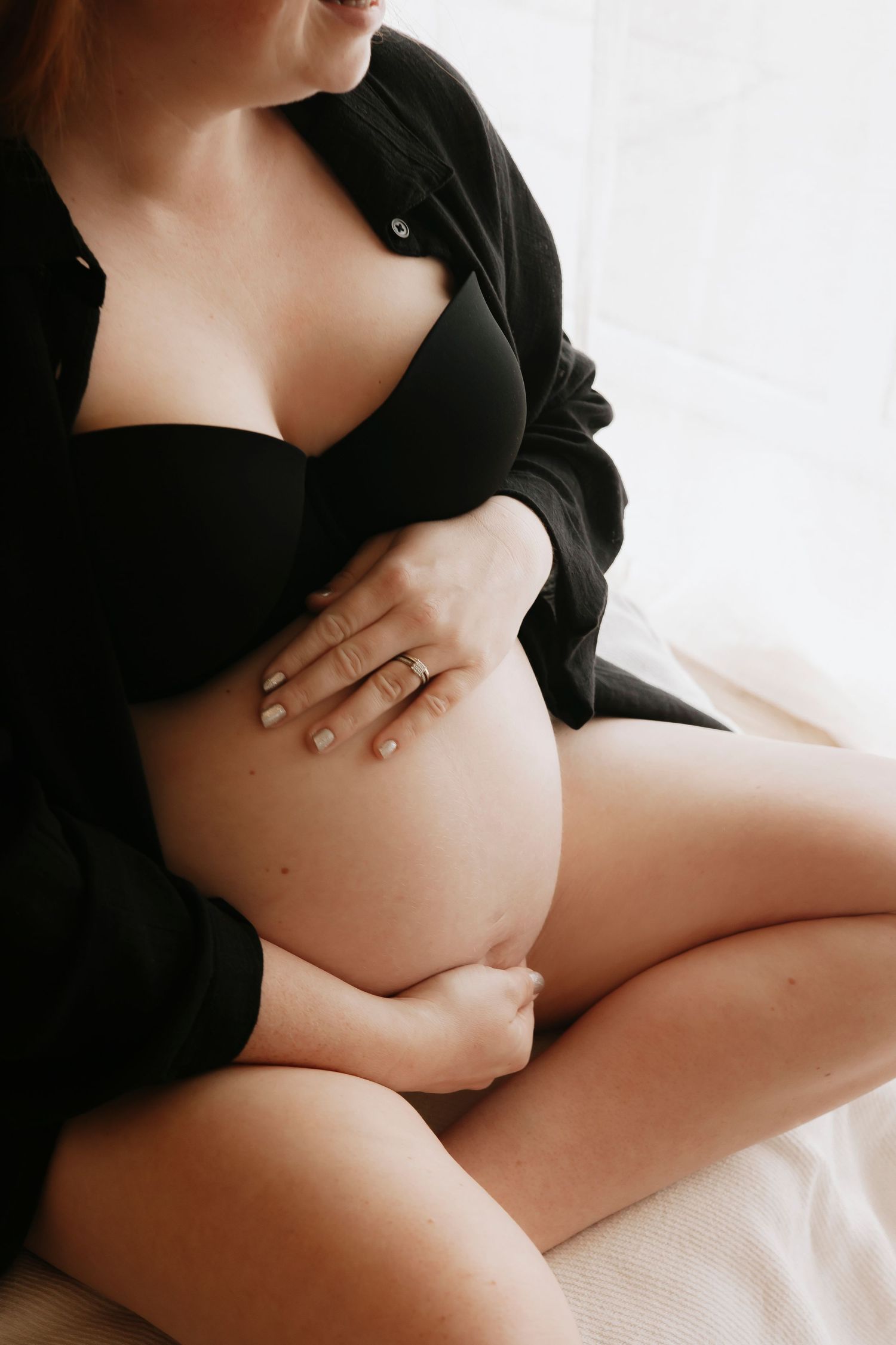 Artistic maternity photos showing pregnant belly in black lingerie against white background.