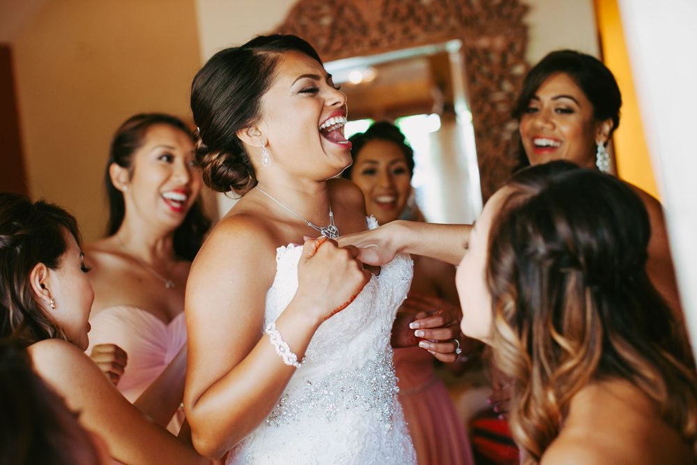 A group of bridesmaids and bride share joyful laughter during wedding preparations.