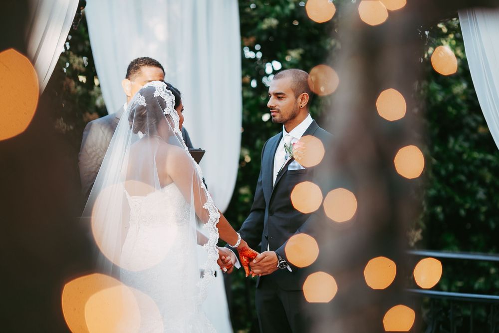Wedding couple shares an intimate moment under glowing string lights during their outdoor evening celebration.
