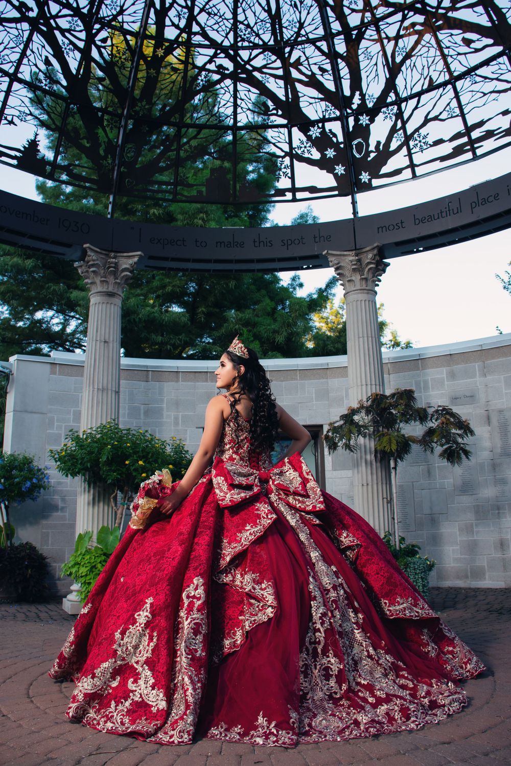 Dramatic red ball gown with silver embellishments photographed at a columned memorial.