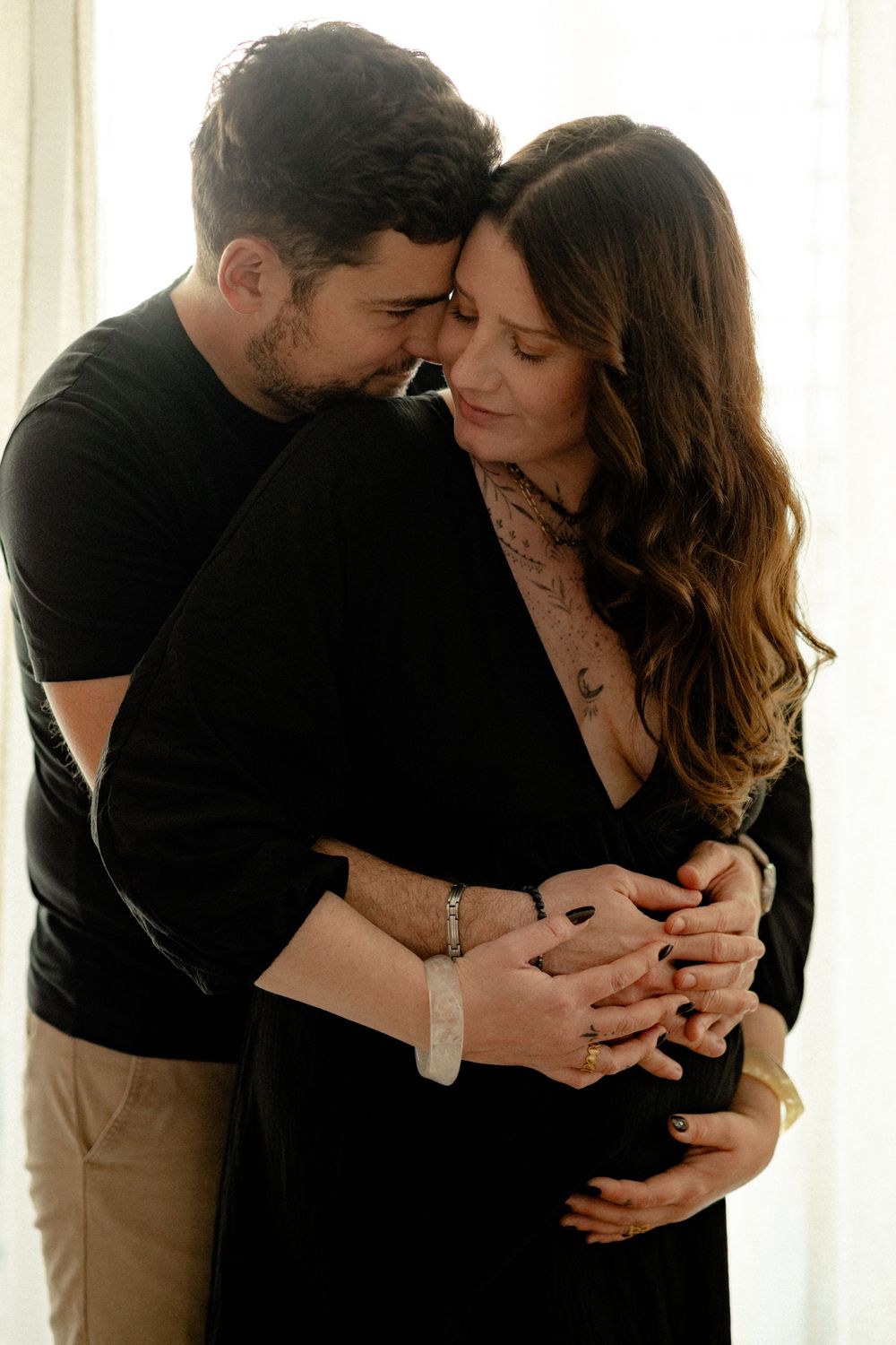 Intimate couple photoshoot with tender moments captured in natural window lighting.