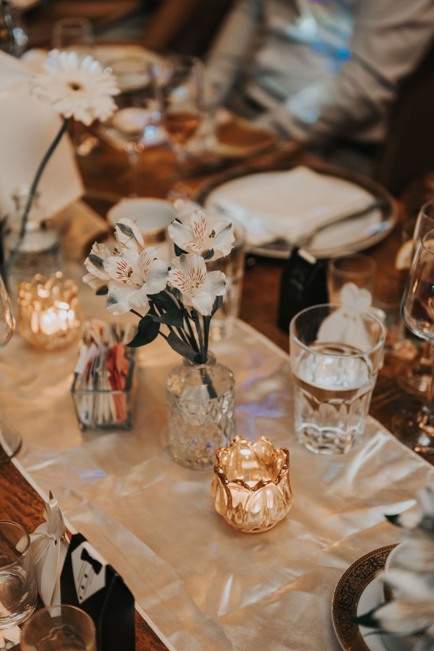 Elegant wedding reception table decor with white flowers in crystal vases and warm candlelight creating a romantic ambiance.
