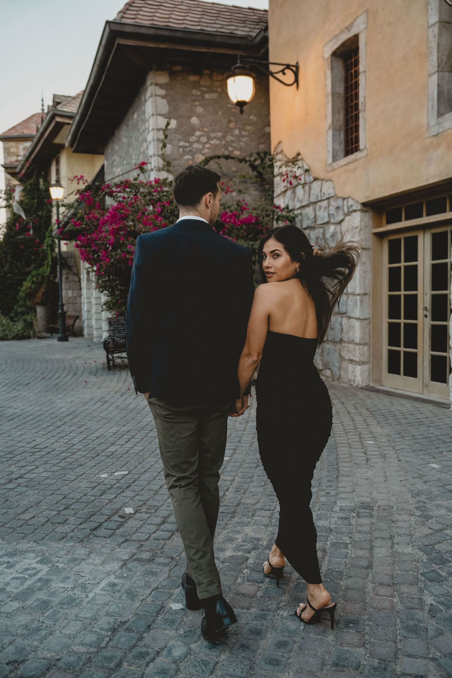 Romantic couple walking through charming old-town street during engagement photoshoot