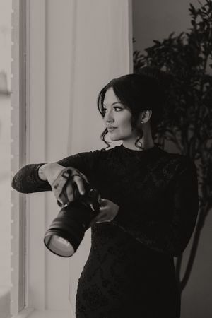 A person in a black outfit poses with boxing gloves in a bright interior setting.