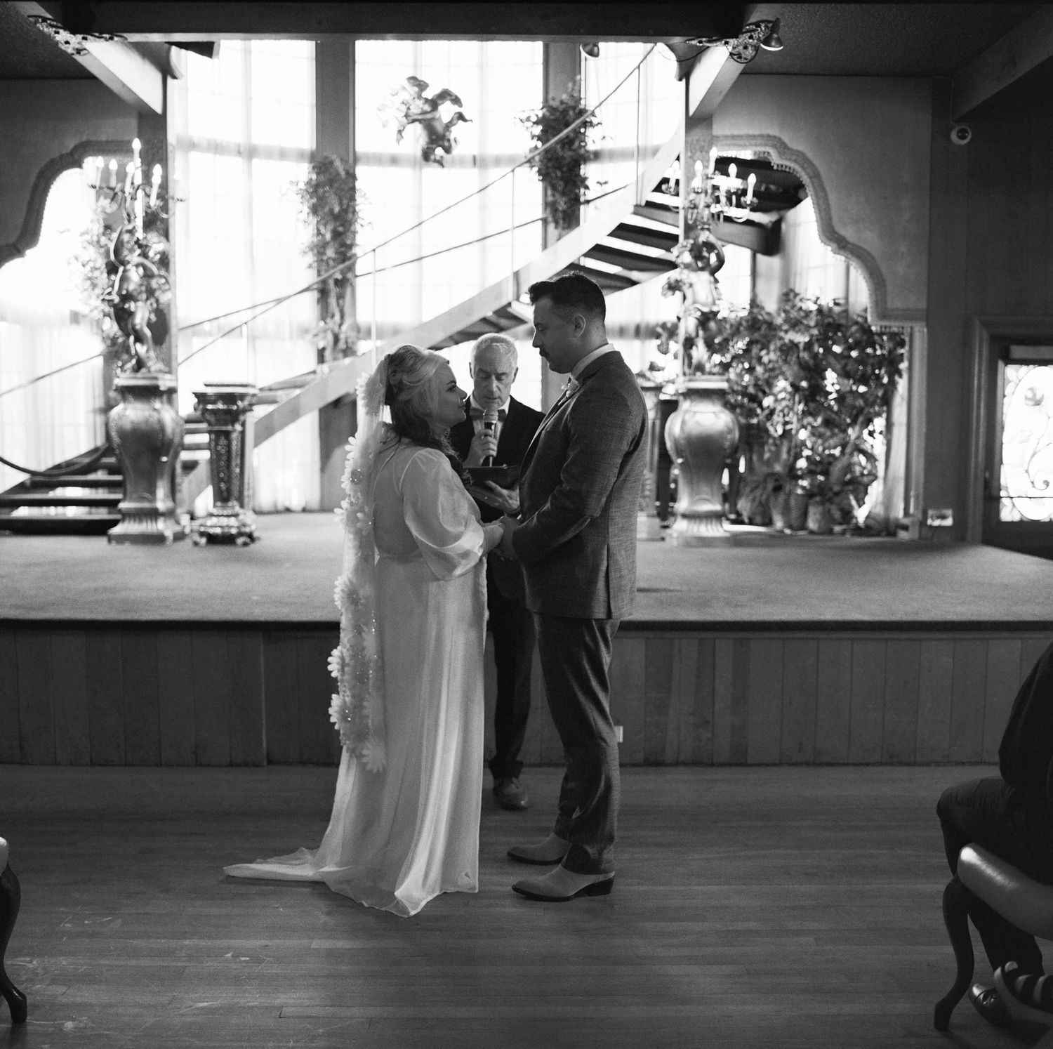 Black and white wedding scene showing guests mingling under covered outdoor venue.