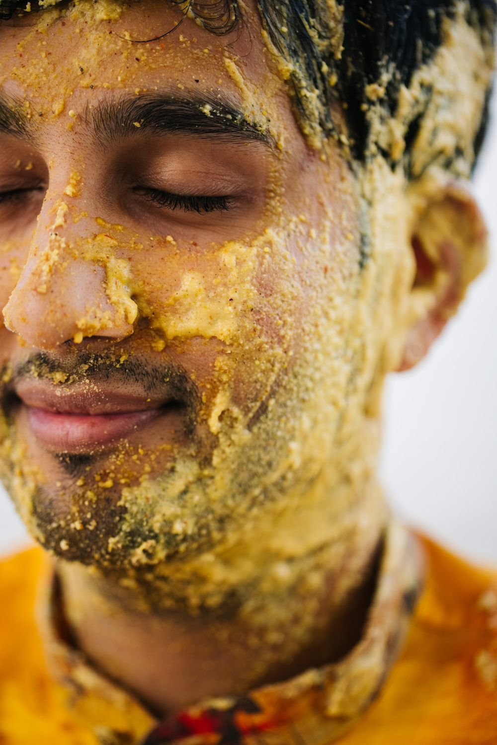 Close up portrait showing turmeric paste applied on face during traditional Indian Haldi ceremony.