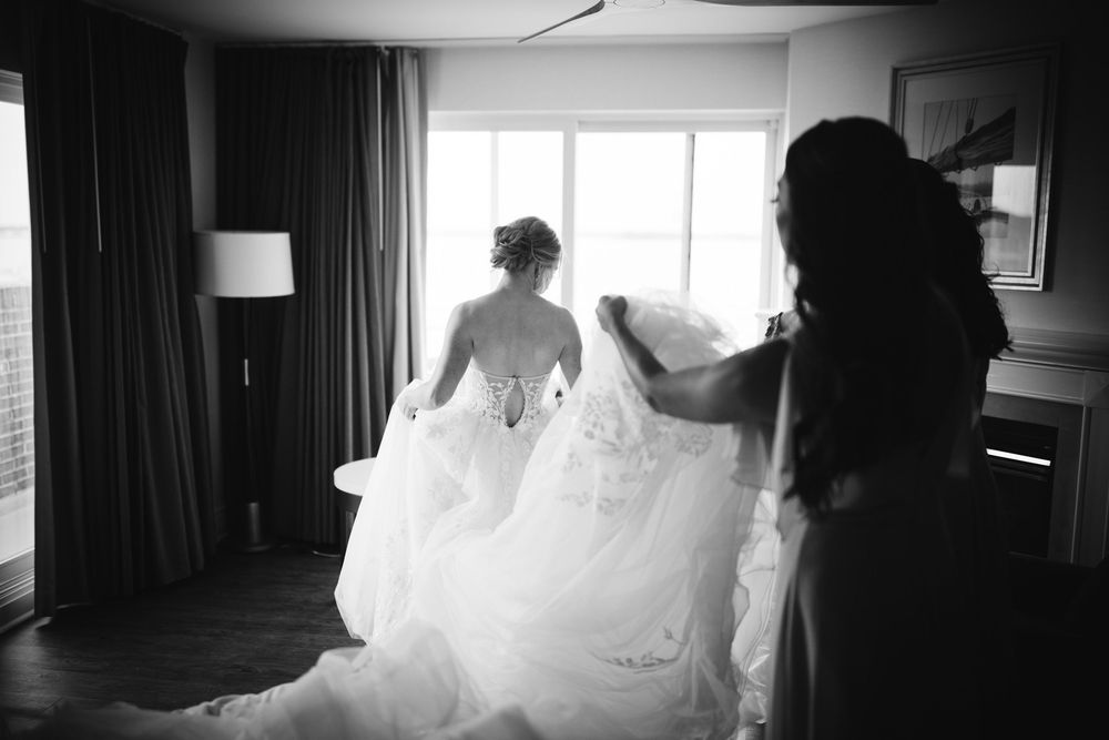 Black and white photo showing the silhouette of a bride getting ready in front of a window.