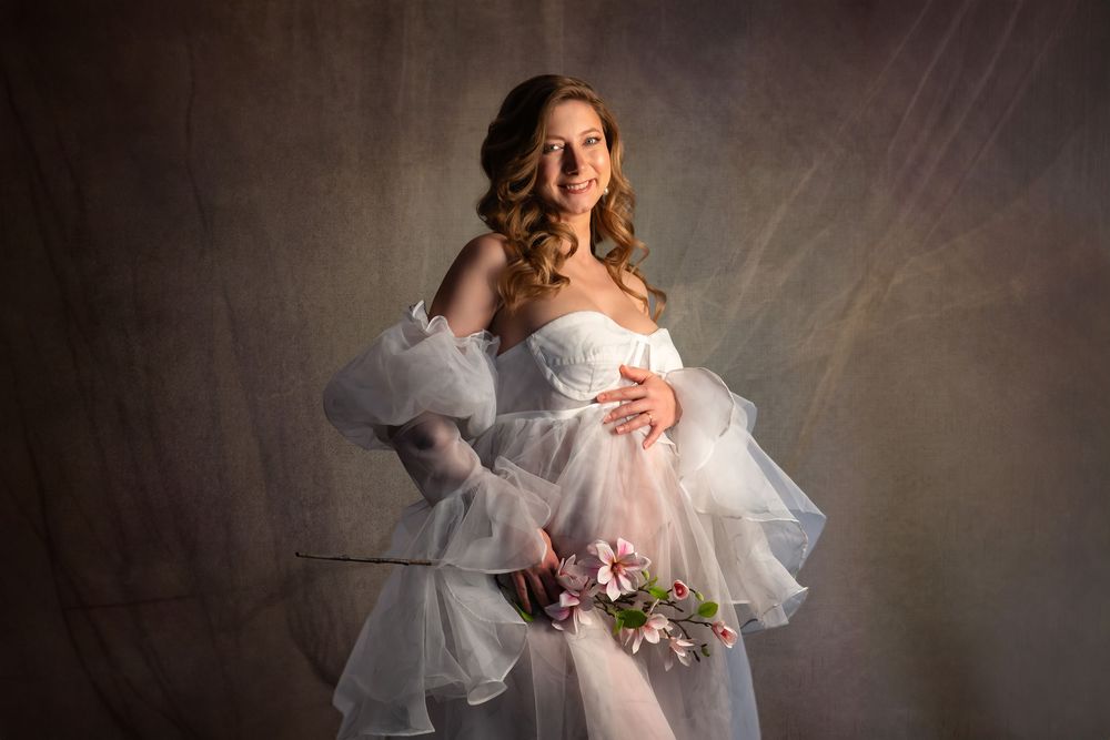 Romantic studio photography with soft lighting highlighting layers of sheer white fabric and floral details.