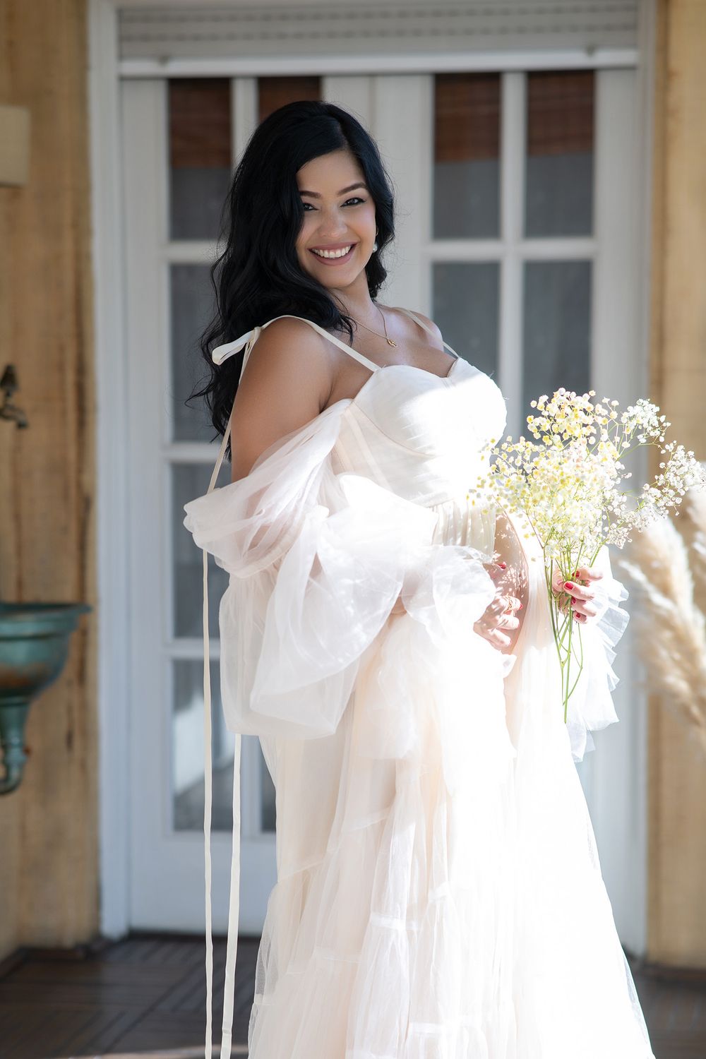 A person in a flowing white off-shoulder dress spins gracefully while holding delicate baby's breath flowers.