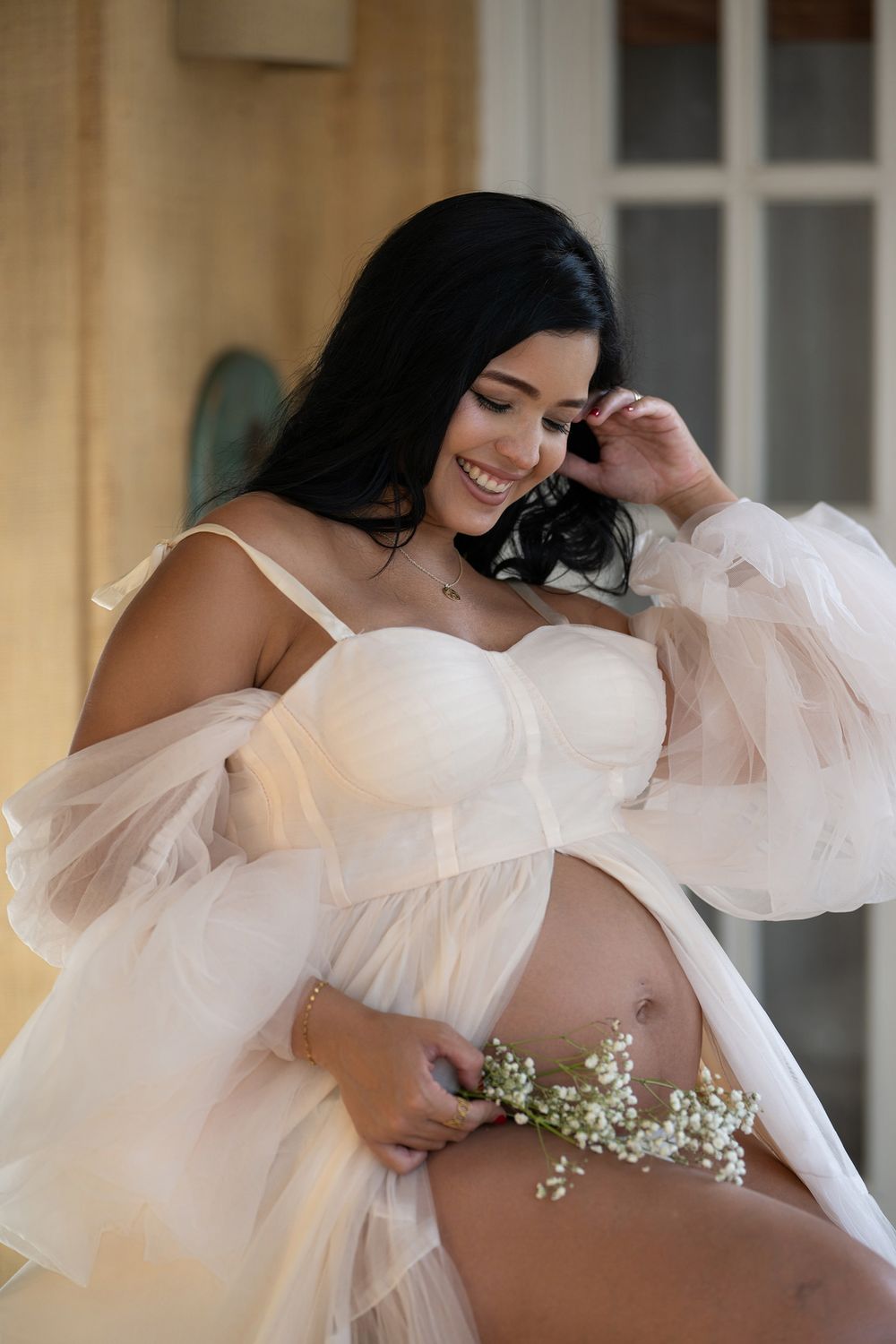 Artistic maternity photos featuring flowing white tulle fabric and delicate baby's breath flowers.