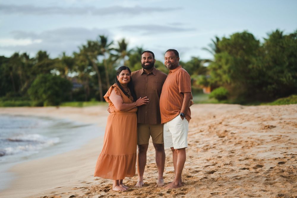 Family members walking together along a tropical beach with palm trees in the background.