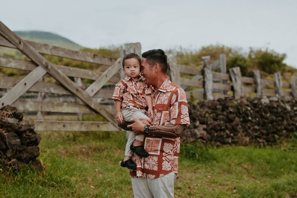 A tender moment between parent and child standing by a rustic stone wall in the countryside.