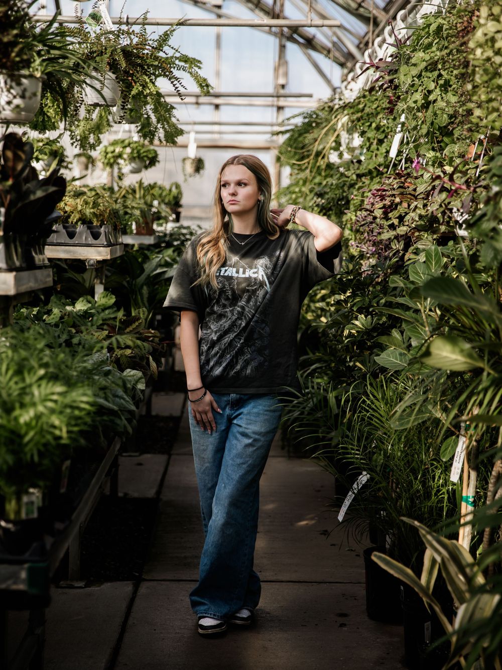 Artistic portrait session among potted plants in a sunlit greenhouse.