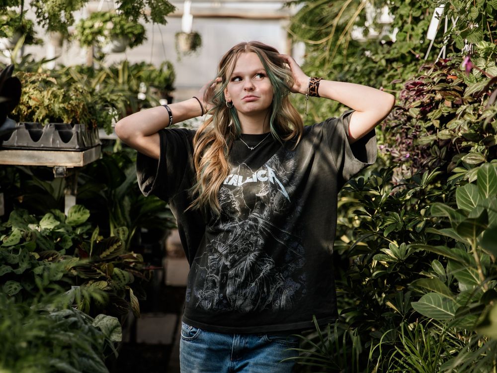 A casual photoshoot in a greenhouse with lush greenery and natural lighting.