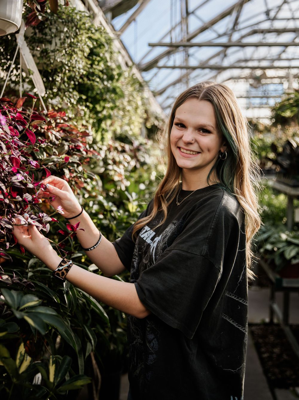 Creative portrait session with red flowers in a bright greenhouse setting.