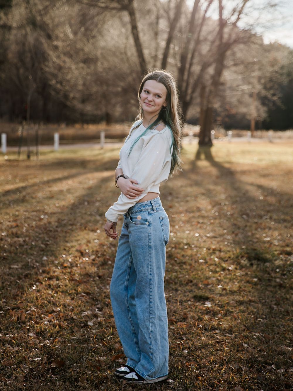 Autumn outdoor portrait session with fallen leaves and bare trees.