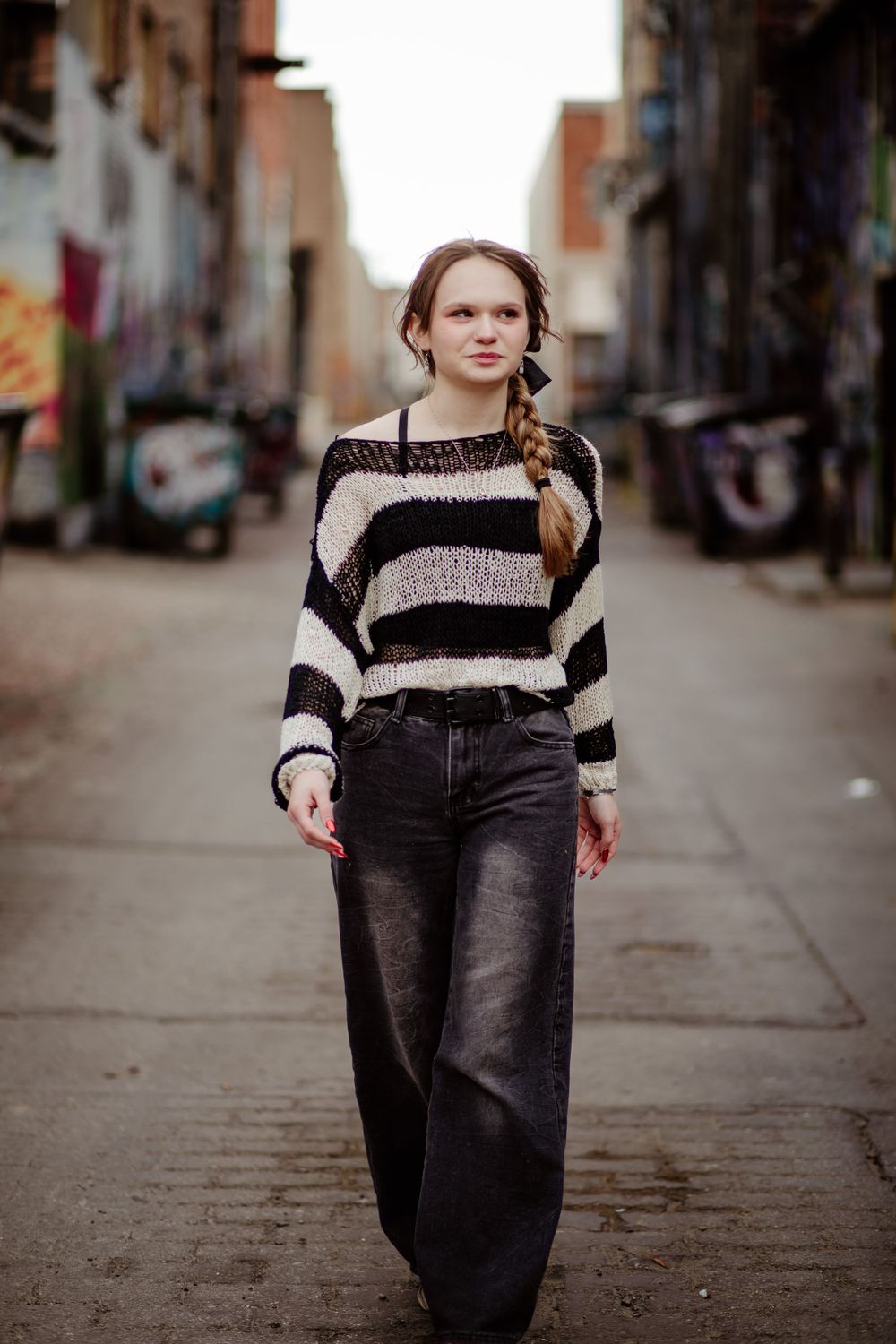 Urban street photography featuring striped knitwear and denim in an alley setting.