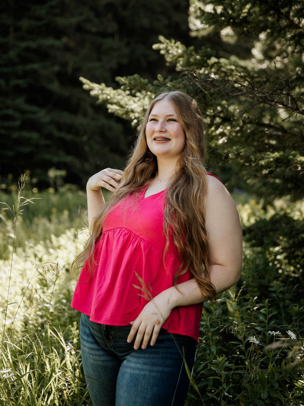 Joyful outdoor portraits in a red top against a forest backdrop.