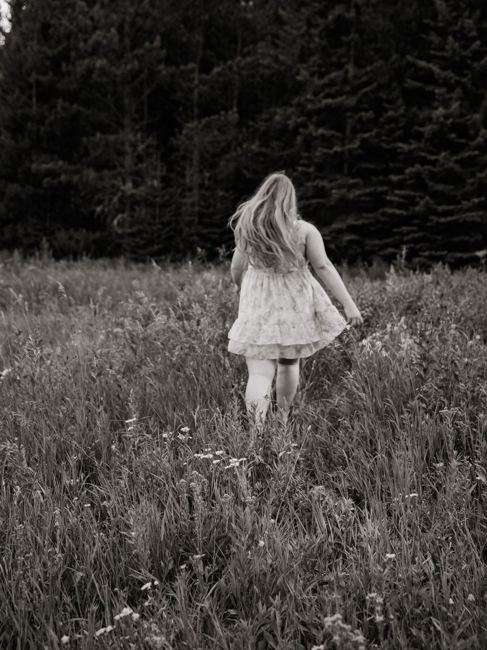 Ethereal black and white photos of someone walking through a wildflower meadow.