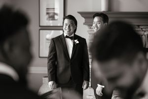 Black and white photo of groomsmen sharing a joyful moment before the ceremony.