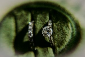 A close-up macro photograph of sparkling diamond rings with a green blurred background.