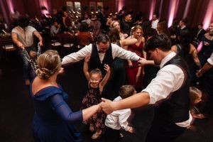 Energetic dance party at wedding reception with guests celebrating on darkened dance floor.