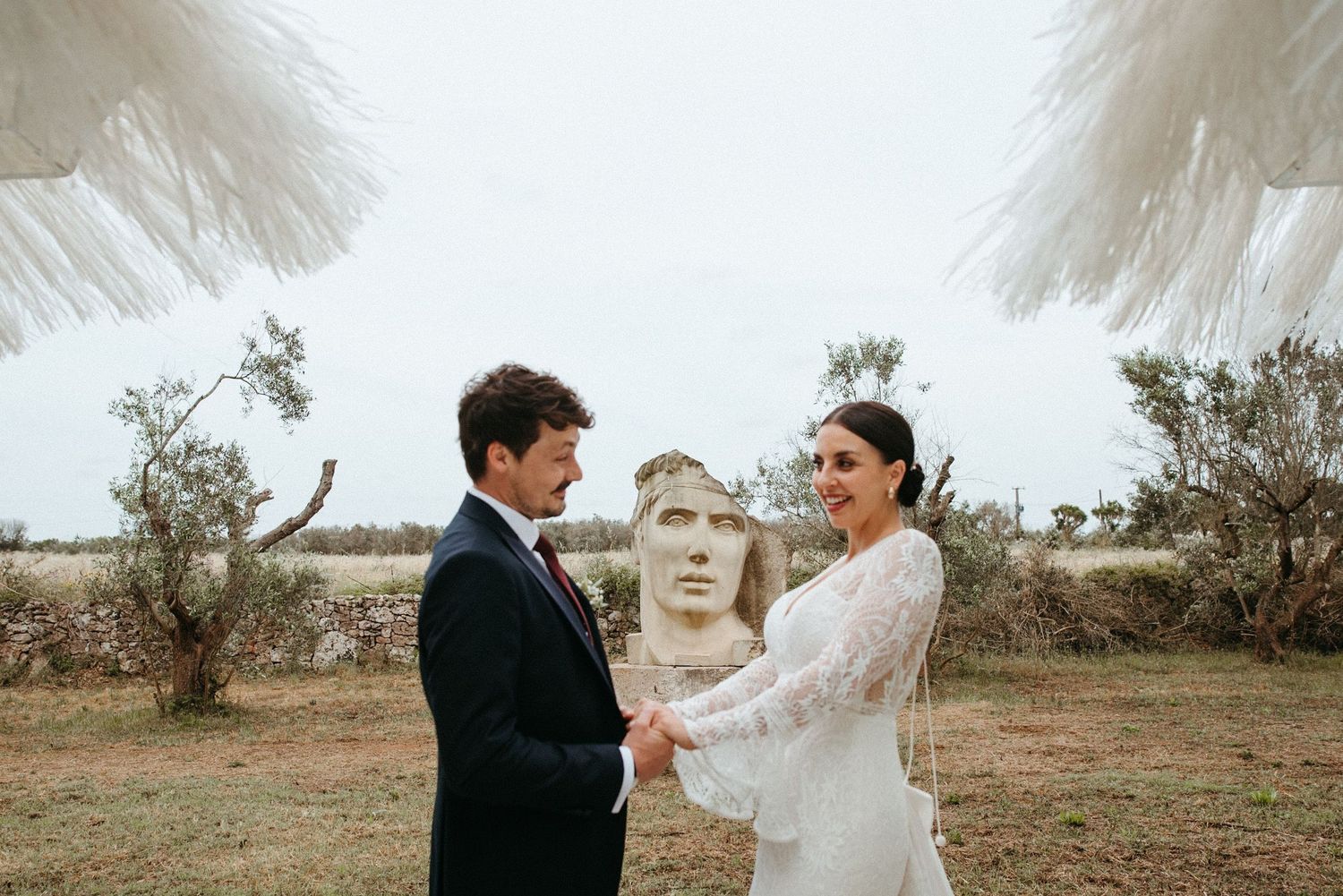 Wedding couple sharing intimate moment in rustic outdoor setting with flowing veil.
