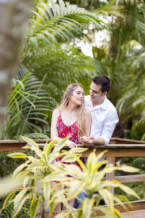 Romantic couple sharing a tender moment on a wooden bridge surrounded by lush tropical greenery.