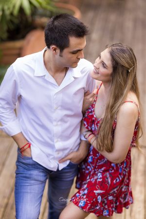 A couple in a romantic moment, man in white shirt and jeans, woman in red floral dress, gazing at each other outdoors.