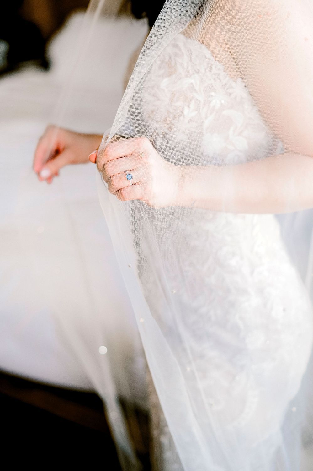 Close-up detail of delicate white tulle fabric being gathered or adjusted, showing the soft texture and layers.